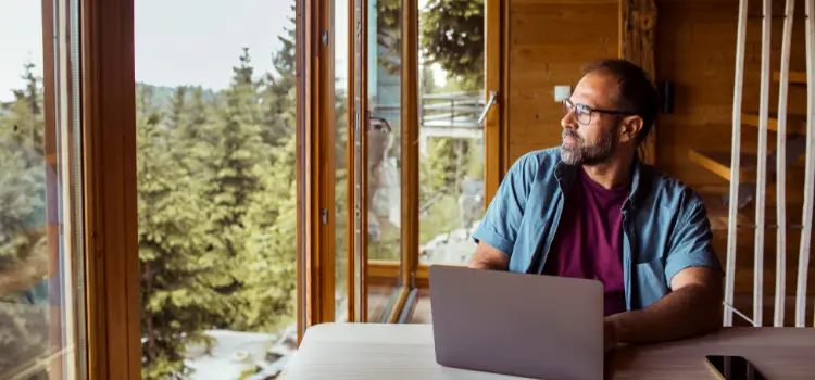 Remote worker sitting at desk with laptop in secluded wooded area